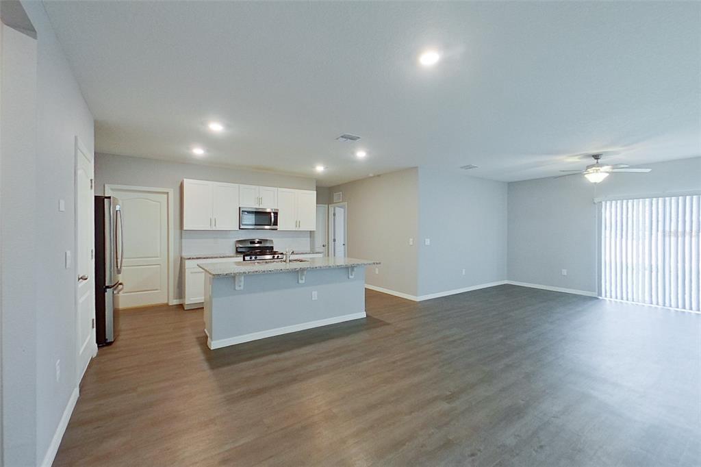 An open-concept kitchen with white cabinets and a granite island overlooks a spacious living area — 32217 EDSON AVENUE, LEESBURG, FL