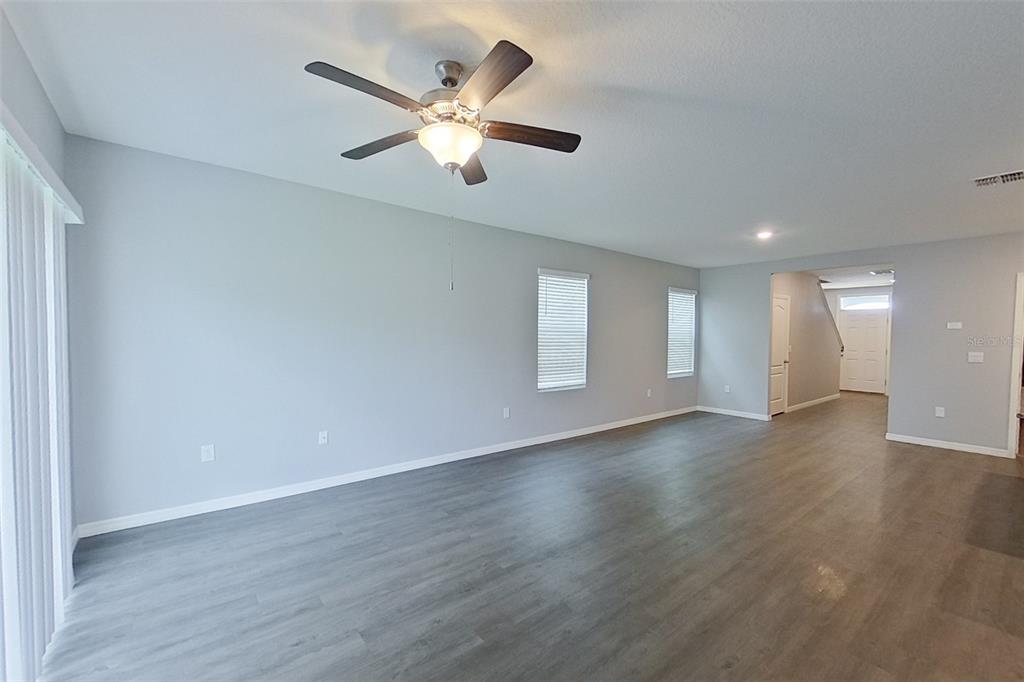 An empty living room features light gray walls, wood-look flooring, and a ceiling fan — 32217 EDSON AVENUE, LEESBURG, FL