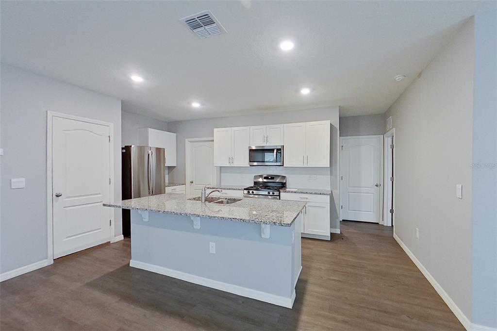 A kitchen features white cabinets, granite countertops, stainless steel appliances, and a central island — 32217 EDSON AVENUE, LEESBURG, FL