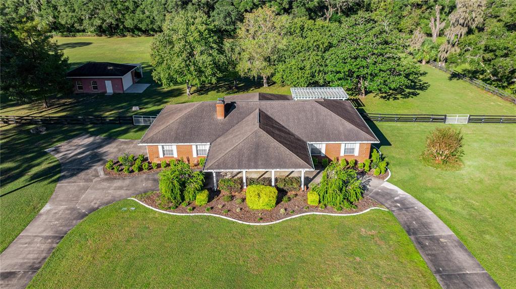 An aerial view shows a brick house with a dark roof, driveway, and surrounding lawn — 9812 SW 74TH AVENUE, OCALA, FL