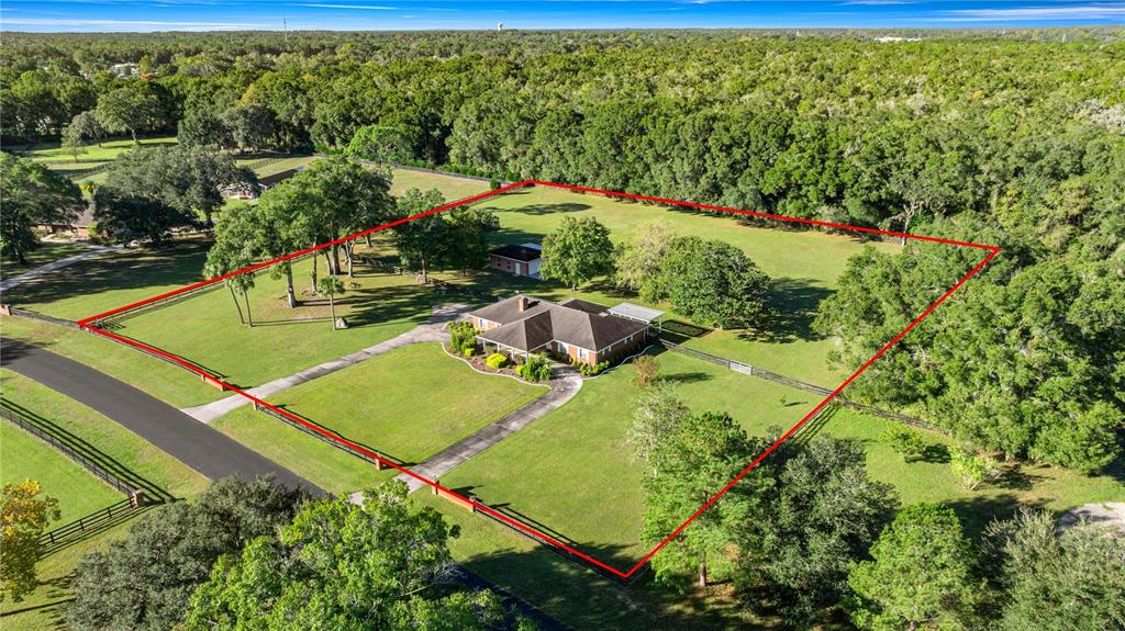 An aerial view shows a single-story house with a driveway on a large, fenced grassy lot — 9812 SW 74TH AVENUE, OCALA, FL