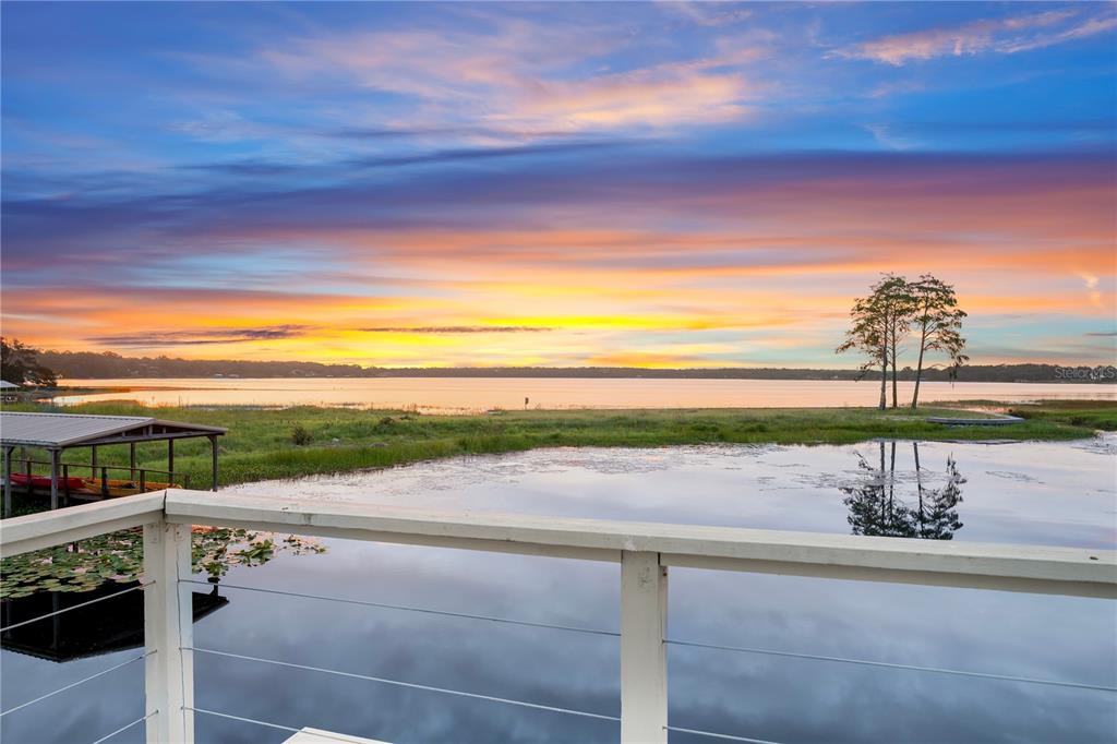 A view of a lake at sunset from a wooden deck with a boat dock — 4931 DORA DRIVE, MOUNT DORA, FL
