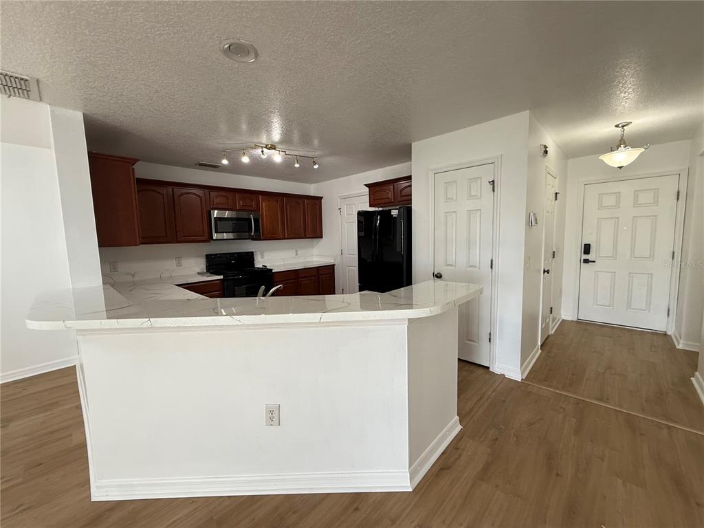 A kitchen with dark wood cabinets, black appliances, and a white quartz breakfast bar — 2573 AVENTURINE STREET, KISSIMMEE, FL
