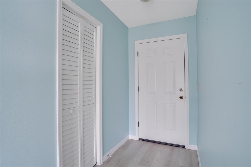 An entryway features light blue walls, a white louvered closet door, and light wood flooring — 216 FAIR WINDS DRIVE UNIT 216, NOKOMIS, FL