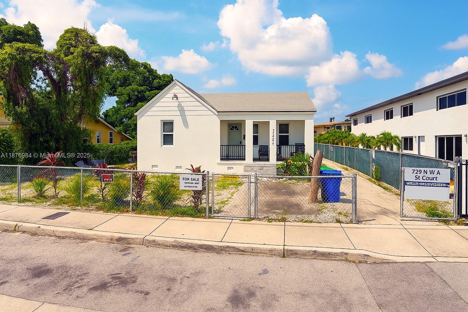 A white single-story house with a front porch sits behind a chain-link fence — 7814 NW 5th Ct, Miami FL 33150, MIAMI, FL