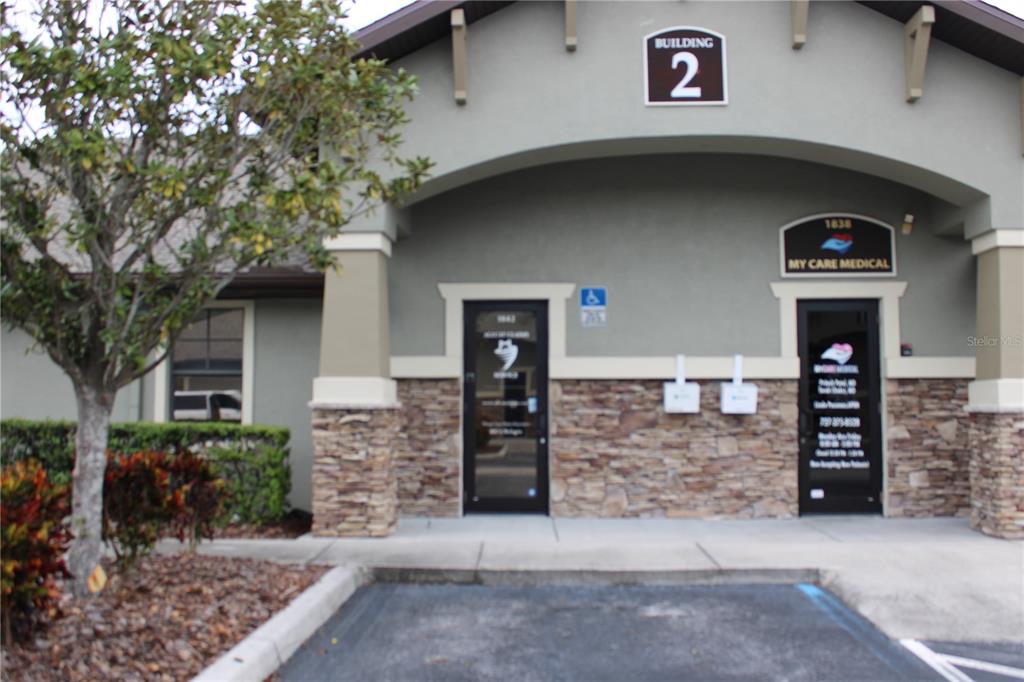 The exterior of a commercial building features two glass entry doors and stone veneer siding — 8820 BELAGIO DRIVE, NEW PORT RICHEY, FL