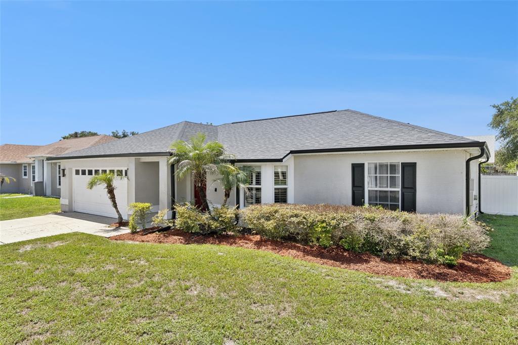 A single-story house with a white stucco exterior, a gray shingled roof, and black shutters — 14004 AMES AVENUE, ORLANDO, FL