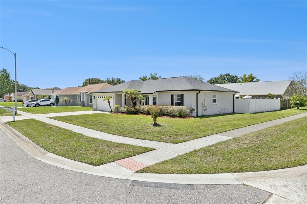 A single-story house with a white exterior, a gray roof, and a corner lot lawn — 14004 AMES AVENUE, ORLANDO, FL