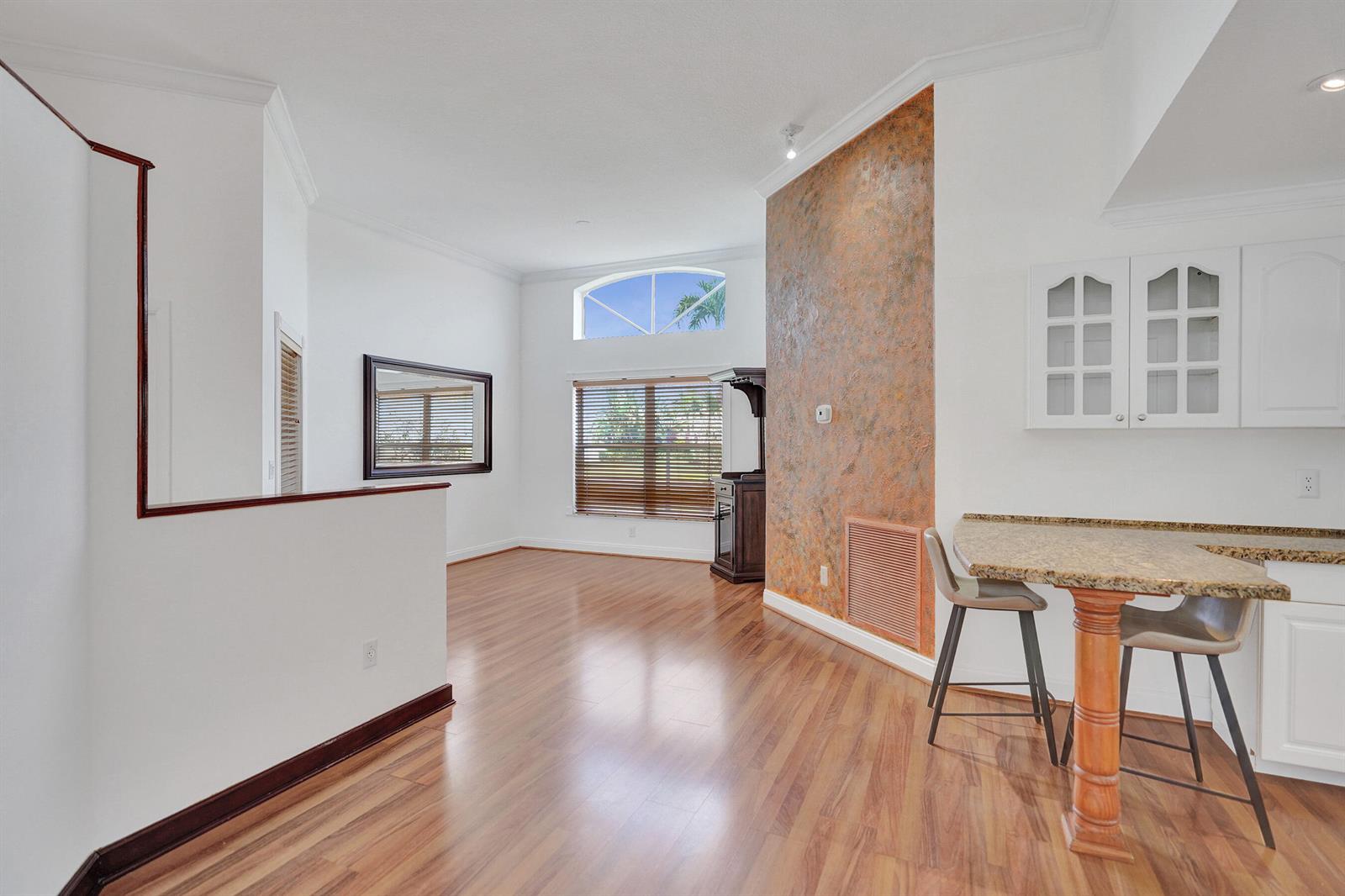 A bright living area features wood-look flooring, a textured accent wall, and a breakfast bar — 6817 Barnwell Drive, Boynton Beach FL 33437, BOYNTON BEACH, FL