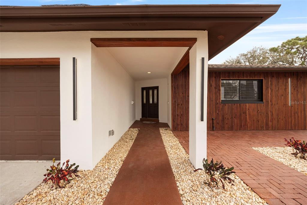 A modern home exterior features a brown garage door, a covered entryway, and wood-slat siding — 5921 DENVER STREET NE, ST PETERSBURG, FL
