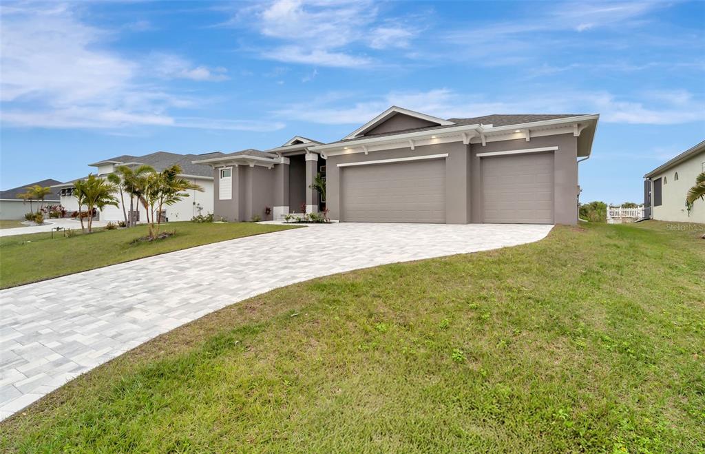 A gray single-story house with a three-car garage and a paved driveway — 10442 WINNIPEG STREET, PORT CHARLOTTE, FL
