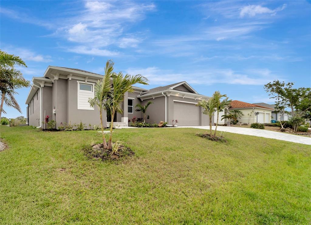 A single-story gray house with a two-car garage and palm trees on a grassy lawn — 10442 WINNIPEG STREET, PORT CHARLOTTE, FL