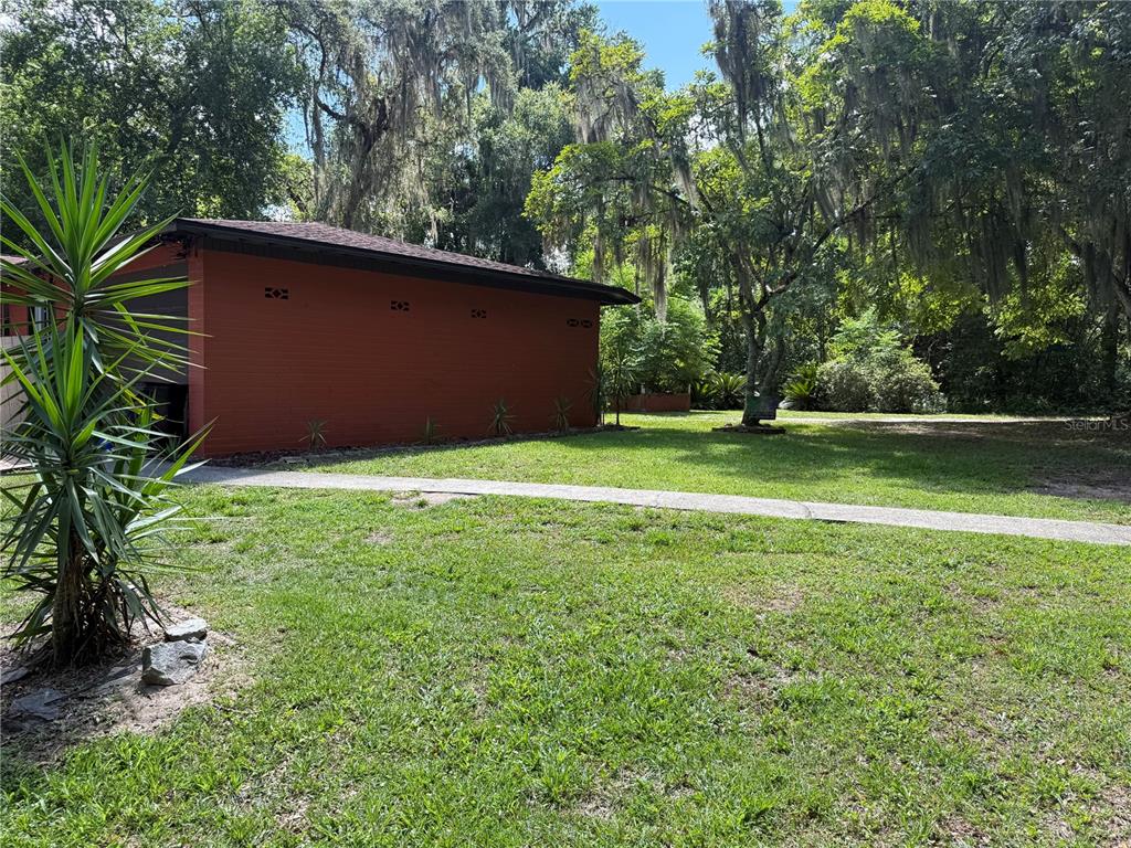 A red detached garage sits on a grassy lawn surrounded by trees with Spanish moss — 1830 SW WILLISTON ROAD, GAINESVILLE, FL