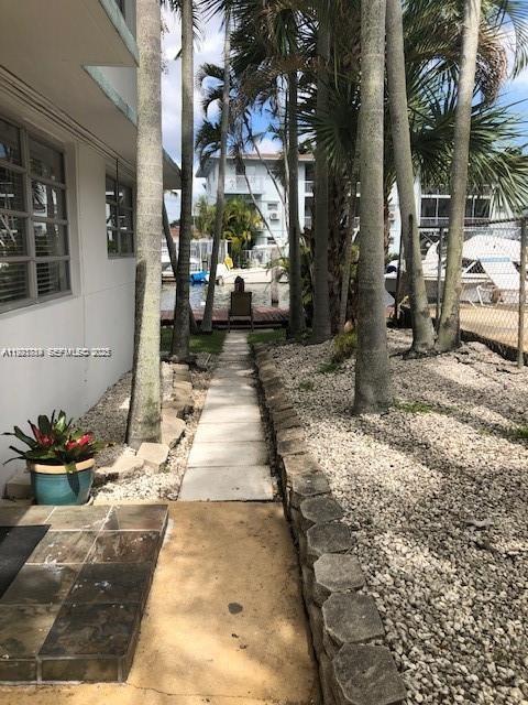 A paved walkway leads between a building and a gravel yard toward a waterfront dock — 645 NE 77th St # 8, Miami FL 33138, MIAMI, FL