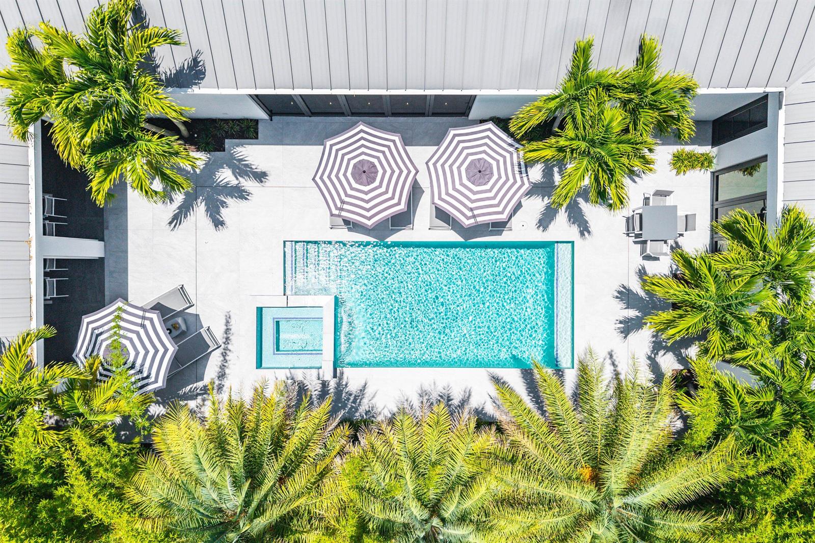 An aerial view of a modern patio featuring a swimming pool, lounge chairs, and palm trees — 1275 N Swinton Avenue, Delray Beach FL 33444, DELRAY BEACH, FL