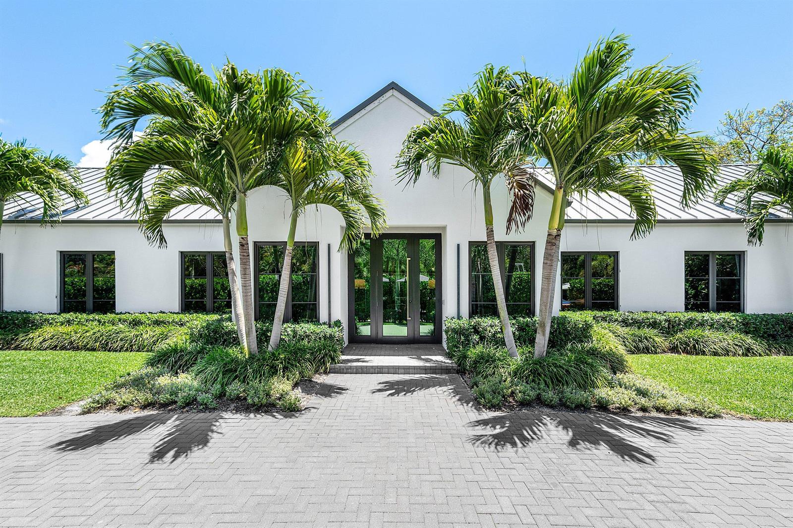 A white house with a metal roof, palm trees, and a paved walkway at the entrance — 1275 N Swinton Avenue, Delray Beach FL 33444, DELRAY BEACH, FL