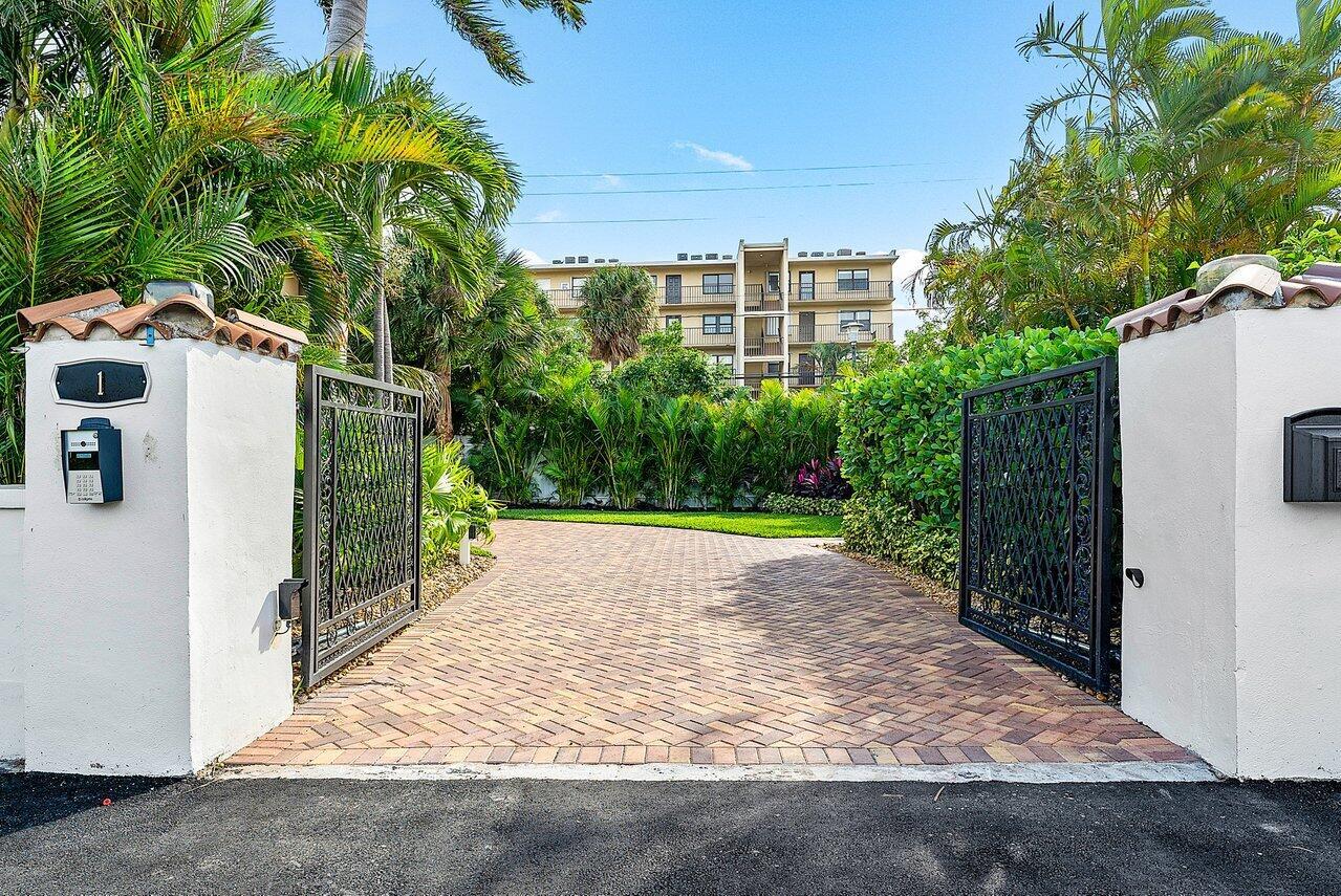 An open wrought iron gate leads to a brick driveway in front of a building — 1 S 18th Avenue S, FL 33460, FL