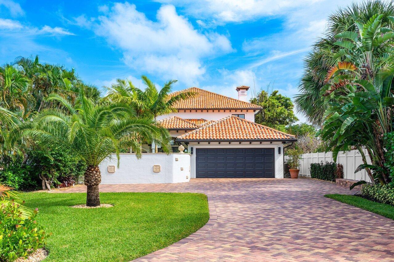 A two-story house with a terracotta tile roof, dark garage door, and a paved driveway — 1 S 18th Avenue S, FL 33460, FL