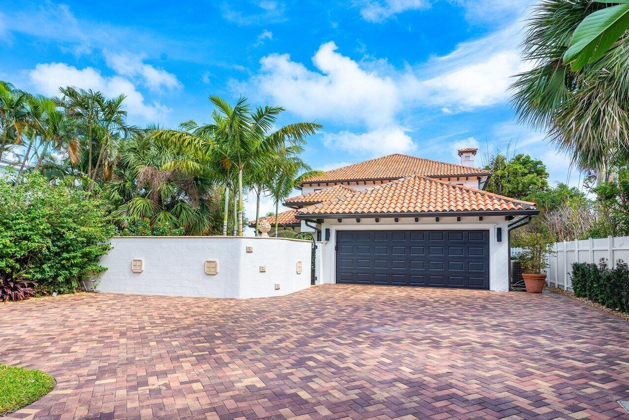 A two-story house with a tiled roof, dark garage door, and a brick-paved driveway — 1 S 18th Avenue S, FL 33460, FL