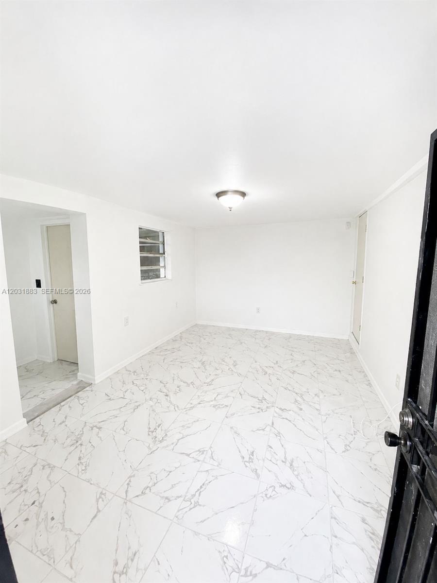 An empty room features white walls, a single window, and white marble-patterned tile flooring — 15720 NW 28th Pl, Miami Gardens FL 33054, MIAMI GARDENS, FL