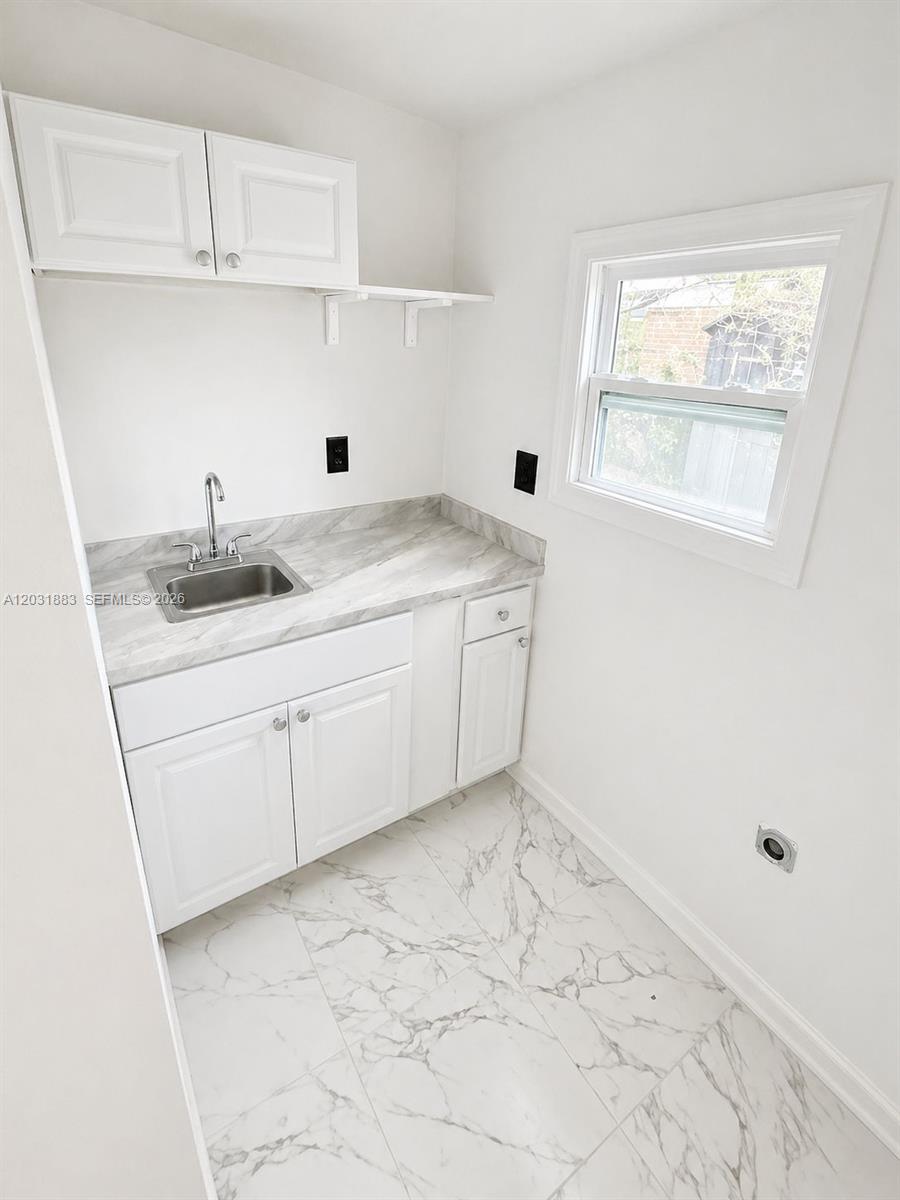 A laundry room features white cabinets, a marble-patterned countertop, a sink, and tiled flooring — 15720 NW 28th Pl, Miami Gardens FL 33054, MIAMI GARDENS, FL