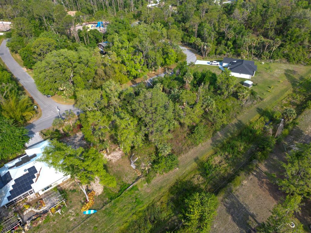 An aerial view shows a wooded residential lot situated between two houses and a road — GALAMBOS STREET, NORTH PORT, FL