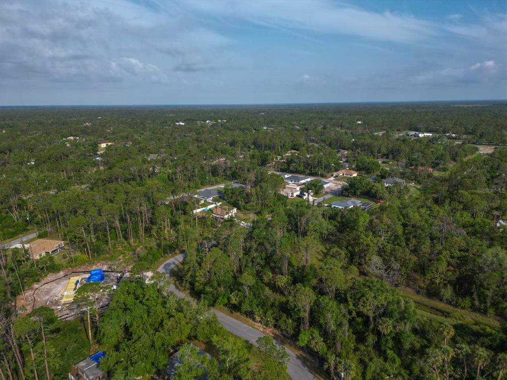 An aerial view shows a residential neighborhood surrounded by dense forest and undeveloped land — GALAMBOS STREET, NORTH PORT, FL