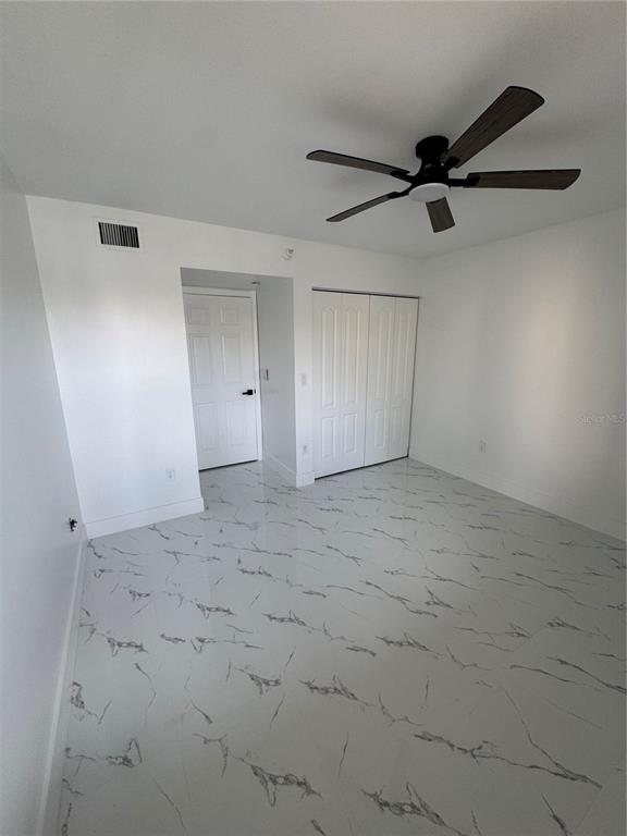A bedroom features white walls, a dark ceiling fan, and white marble-patterned tile flooring — 7751 SOUTHAMPTON TERRACE UNIT 213, TAMARAC, FL