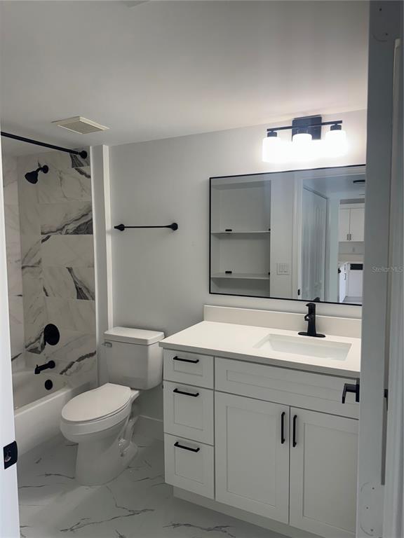 A bathroom features a white vanity, a marble-look tub surround, and black hardware — 7751 SOUTHAMPTON TERRACE UNIT 213, TAMARAC, FL