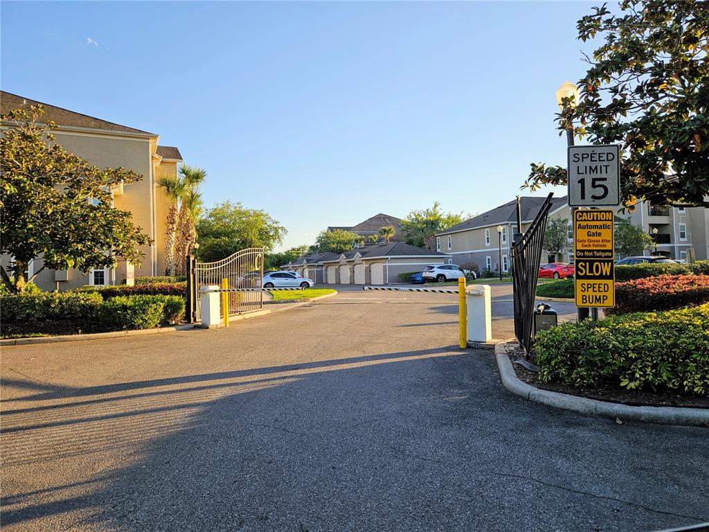 An asphalt driveway leads through an open security gate into a residential apartment complex — 6548 SWISSCO DRIVE UNIT 628, ORLANDO, FL