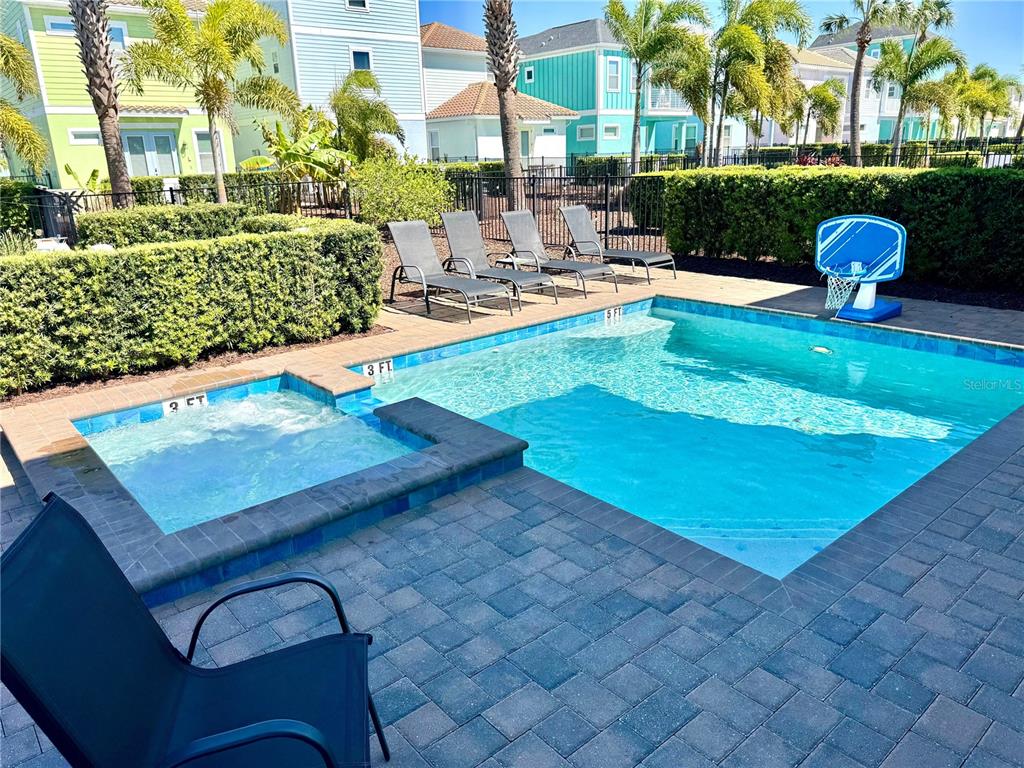 A backyard features a swimming pool with an attached spa, lounge chairs, and a basketball hoop — 8014 KNEE DEEP ROAD, KISSIMMEE, FL