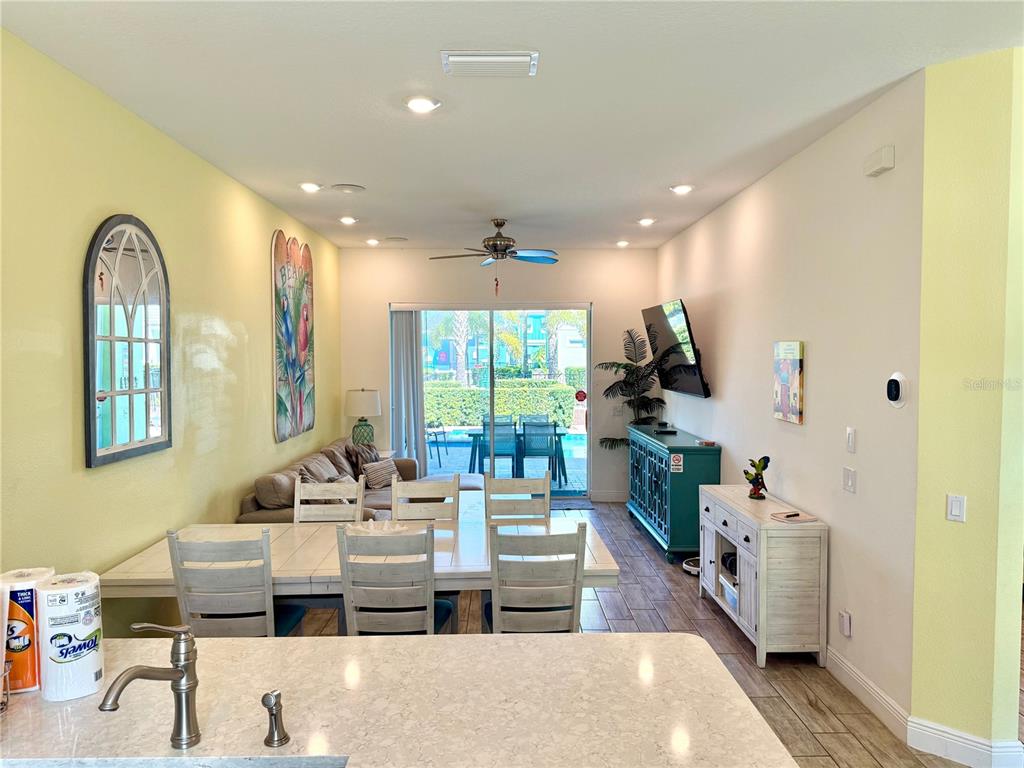A kitchen island overlooks a dining area and living room with sliding glass doors to a pool — 8014 KNEE DEEP ROAD, KISSIMMEE, FL