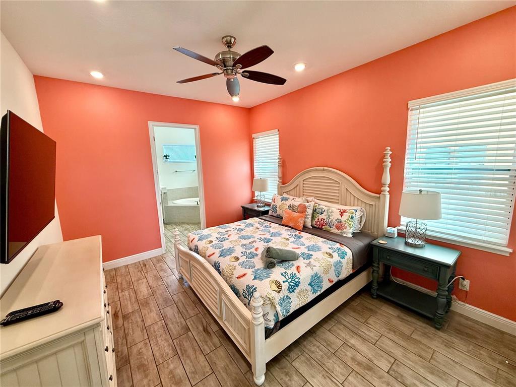 A bedroom with coral walls, a white bed frame, and wood-look tile flooring — 8014 KNEE DEEP ROAD, KISSIMMEE, FL