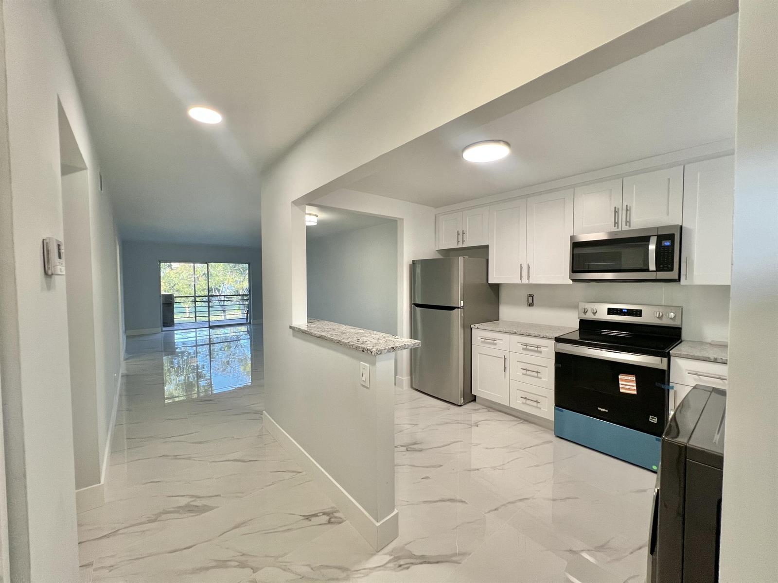 A kitchen with white cabinets, stainless steel appliances, and marble-look tile floors — 601 S State Road 7 # 2c, Margate FL 33068, MARGATE, FL