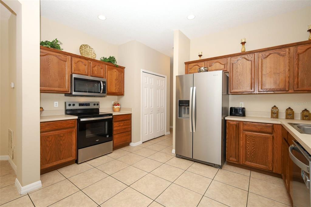 A kitchen with oak cabinets, stainless steel appliances, and light-colored tile flooring — 426 ALEXANDRIA PLACE DRIVE, APOPKA, FL