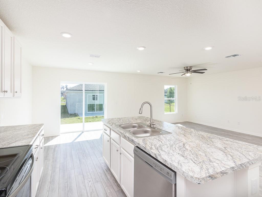 A kitchen with white cabinets, granite countertops, and a center island overlooks a living area — 1359 HAGERICK LANE, NORTH PORT, FL