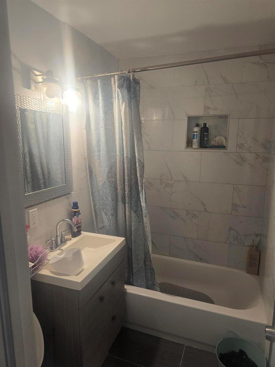 A bathroom features a vanity, a mirror, and a shower-tub combo with white tiled walls — 3016 E Palm Drive, Boynton Beach FL 33435, BOYNTON BEACH, FL