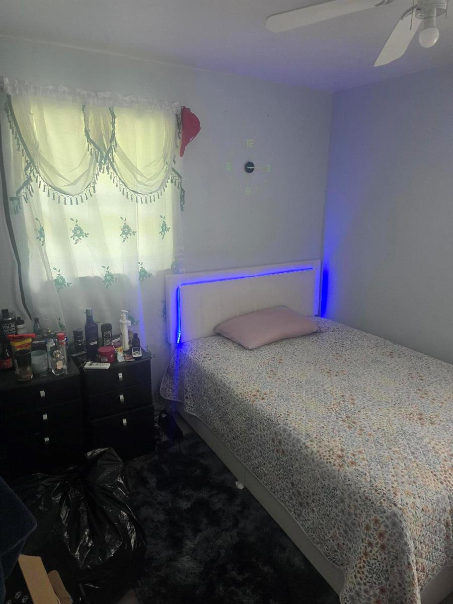 A bedroom features a bed with a blue LED headboard, a floral quilt, and a nightstand — 3016 E Palm Drive, Boynton Beach FL 33435, BOYNTON BEACH, FL