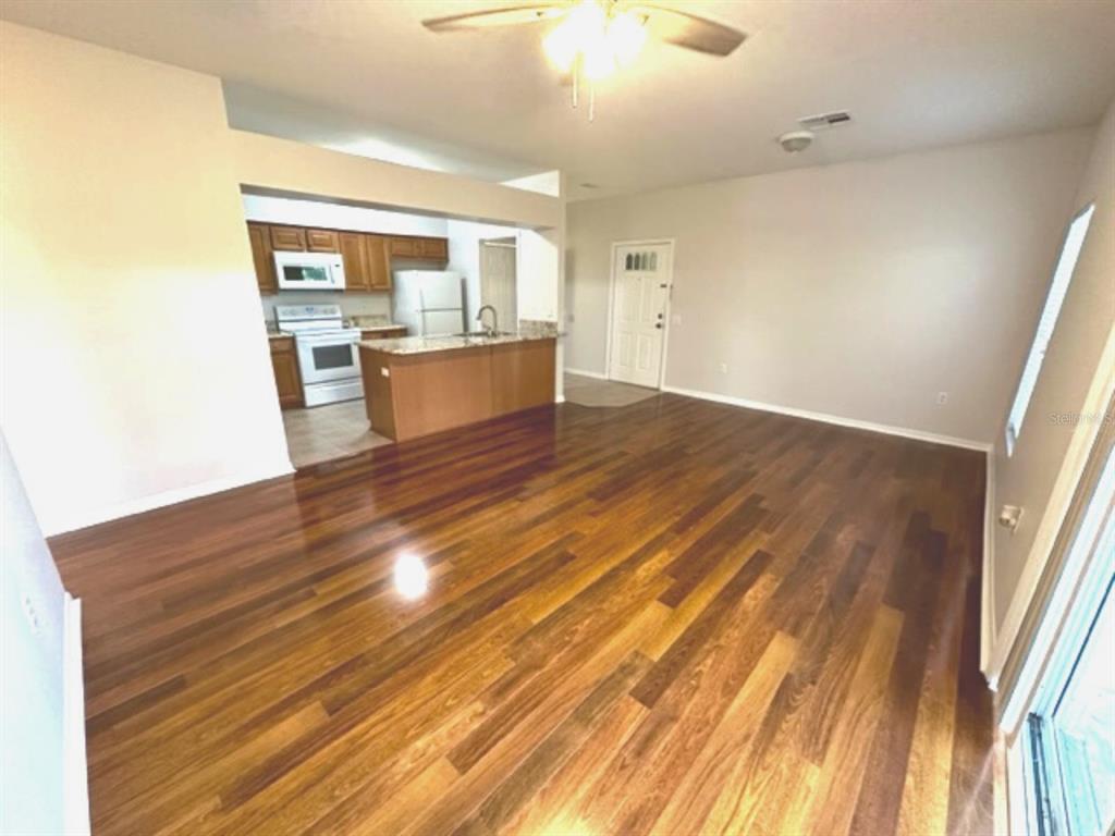 An open-concept living area features dark hardwood flooring, a ceiling fan, and a kitchen island — 903 EAGLE POND DRIVE UNIT 903, WINTER HAVEN, FL
