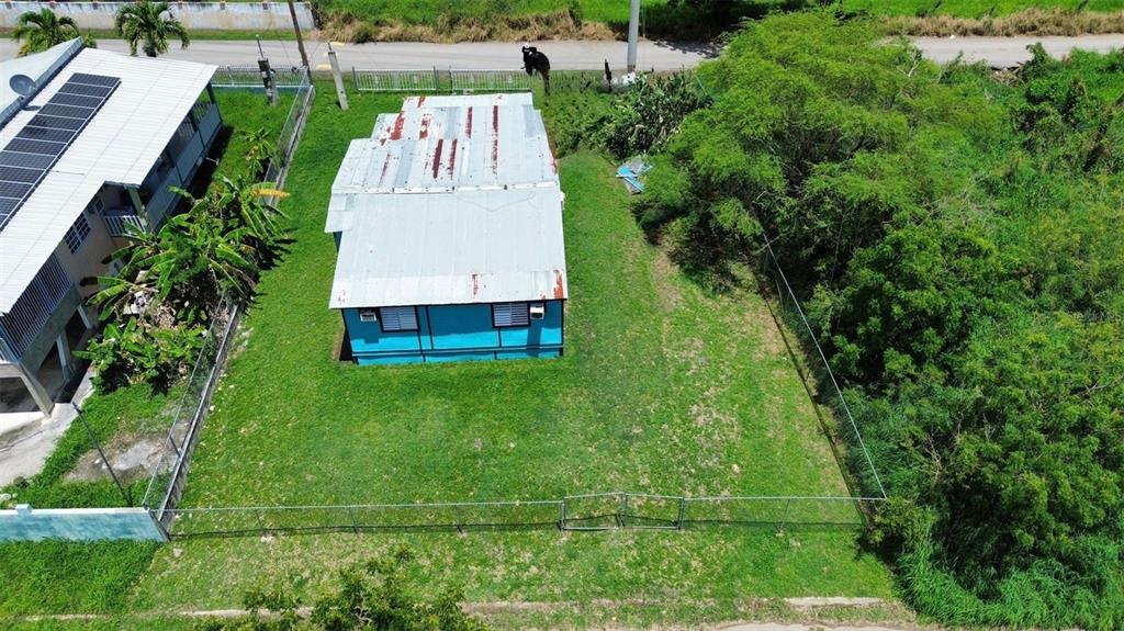 An aerial view shows a blue house with a metal roof on a fenced lot — Sola 10 BO LLANOS COSTA, BOQUERON, PR
