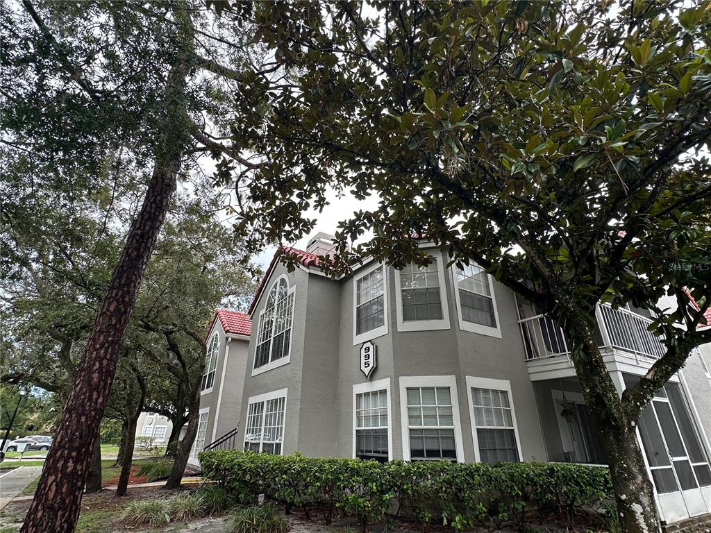 A multi-story gray apartment building with a red tile roof and a screened balcony — 995 NORTHERN DANCER WAY UNIT 201, CASSELBERRY, FL