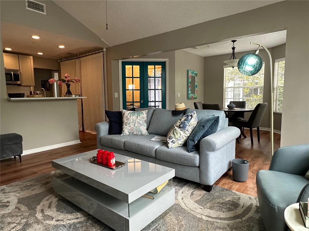 A living room features a grey sofa, a glossy coffee table, and an adjacent dining area — 995 NORTHERN DANCER WAY UNIT 201, CASSELBERRY, FL