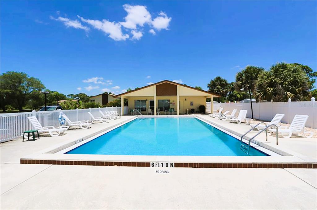 A living room with beige carpet, a brown sofa, two recliners, and a sliding glass door — 6699 SAN CASA DRIVE UNIT L8, ENGLEWOOD, FL