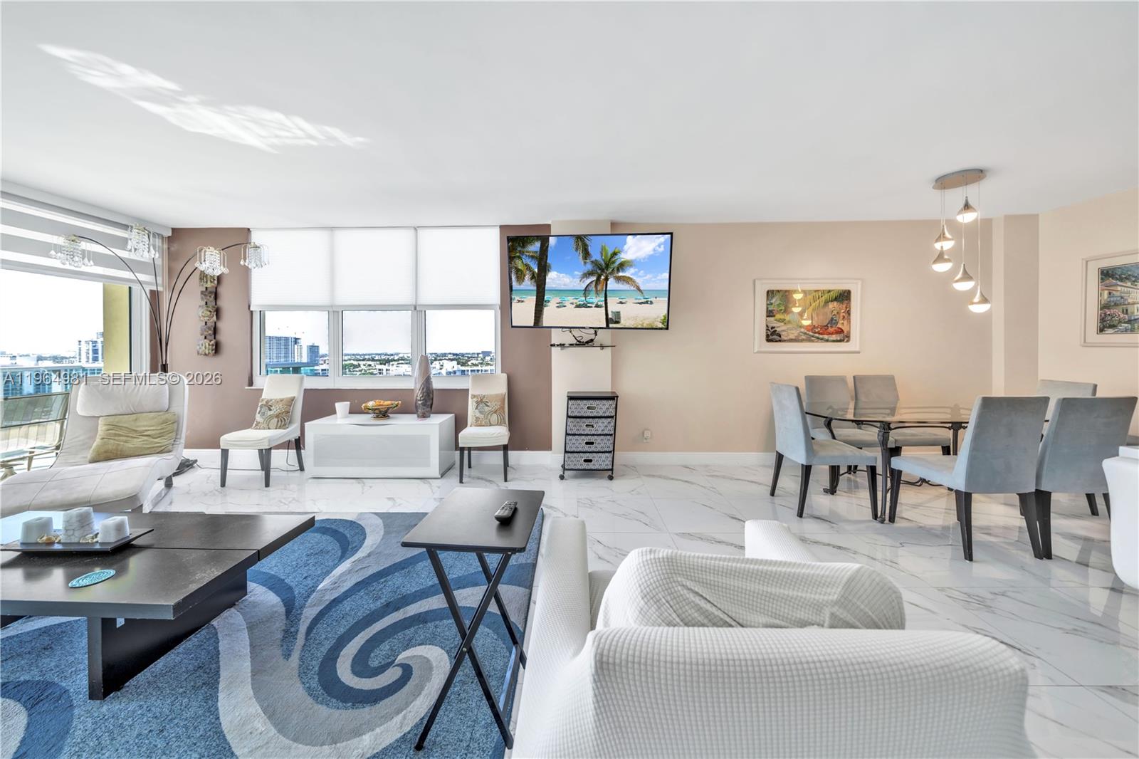 A bright living and dining area features white marble floors, a blue rug, and windows — 2501 S Ocean Dr, Hollywood FL 33019, HOLLYWOOD, FL