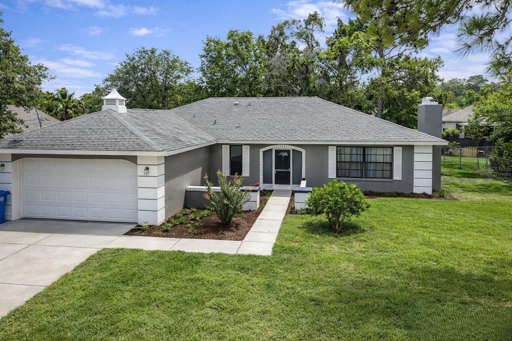 A single-story gray house with a white garage door, white trim, and a front walkway — 5045 KENMORE STREET, SPRING HILL, FL
