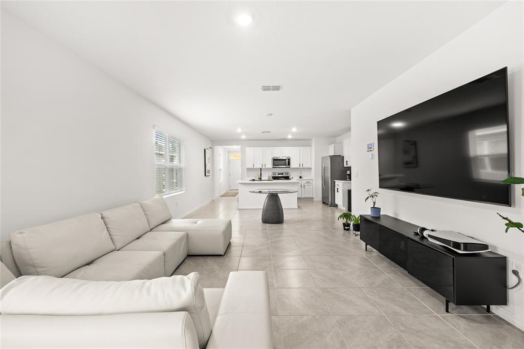 A modern open-concept living room and kitchen with white walls, tile flooring, and white cabinetry — 1663 ROSYDALE CIRCLE, DAVENPORT, FL