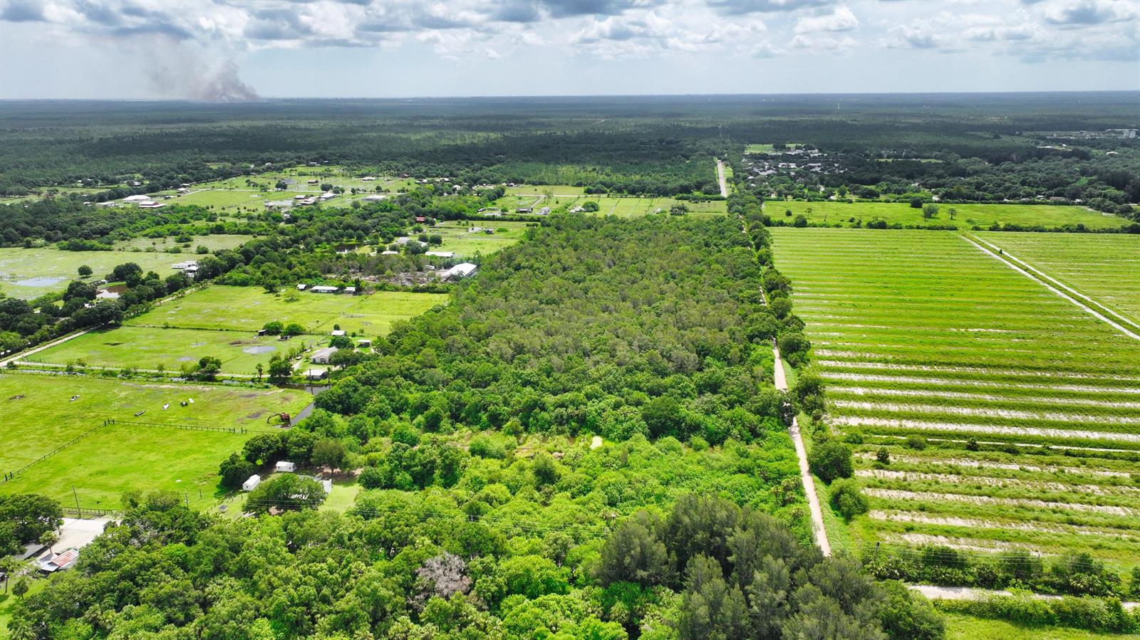 An aerial view shows a large plot of land featuring open fields, dense forest, and farmland — 13380 101st Street, Fellsmere FL 32948, FELLSMERE, FL