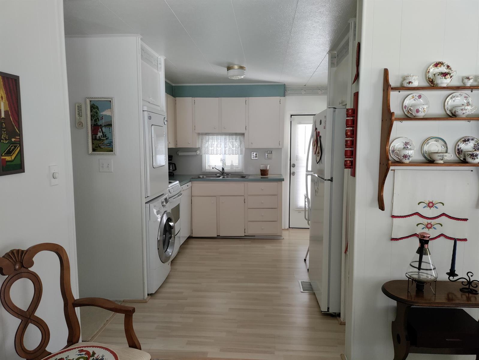 A kitchen with white cabinets, a stacked washer and dryer, and a wooden display shelf — 8270 South Street, Boca Raton FL 33433, BOCA RATON, FL