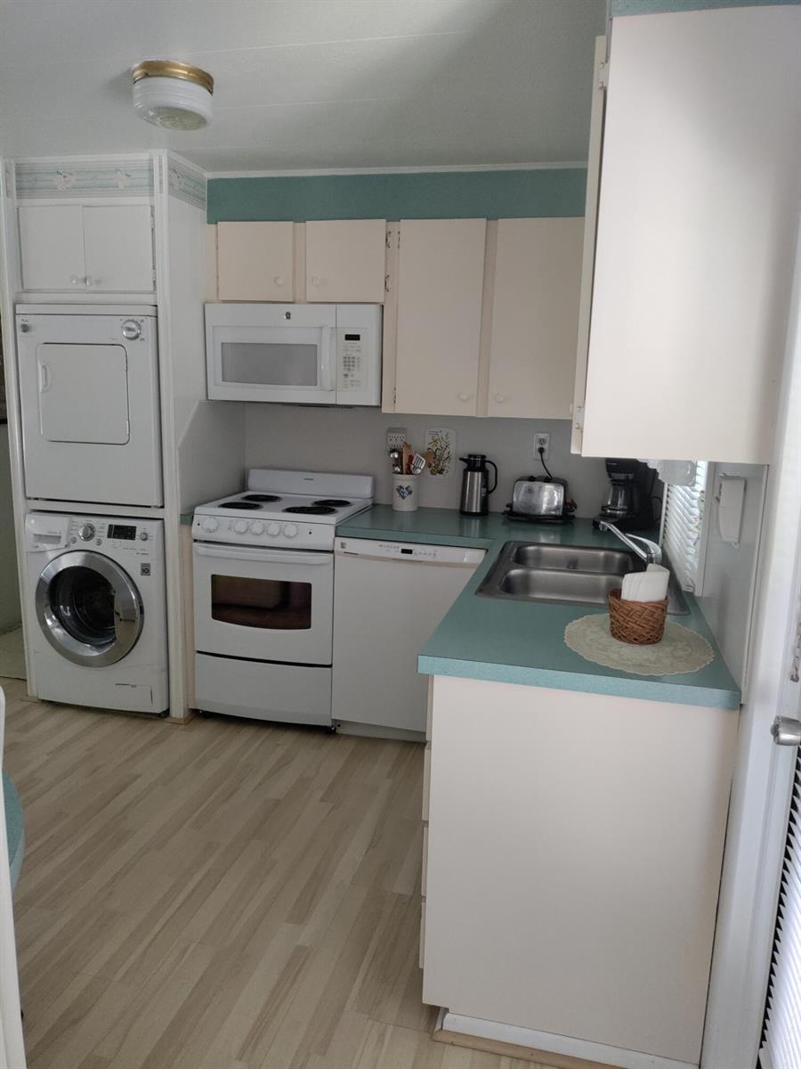 A kitchen features white appliances, light-colored cabinets, and a teal countertop with a stacked washer-dryer — 8270 South Street, Boca Raton FL 33433, BOCA RATON, FL