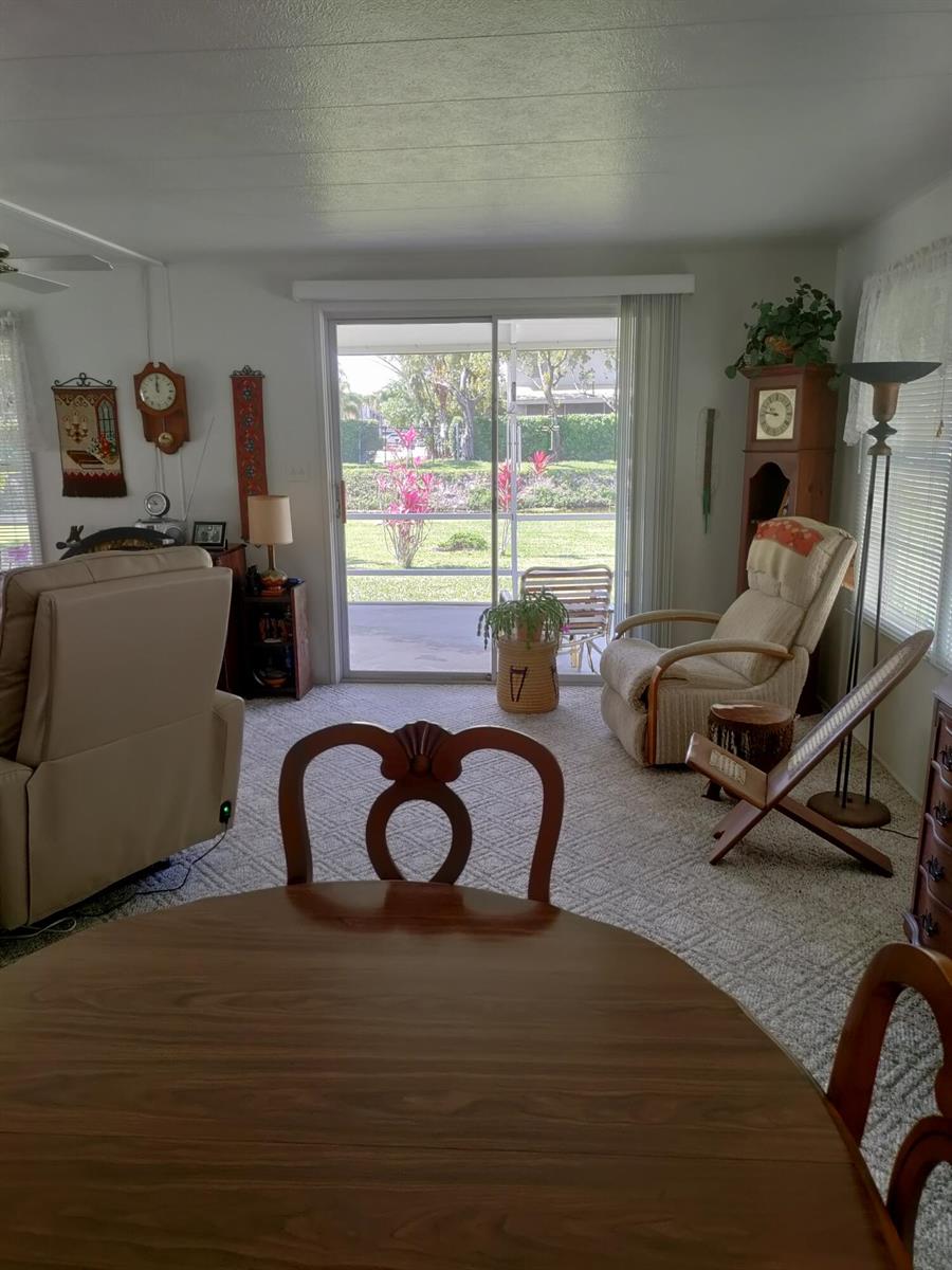A living room with carpeted floors, a sliding glass door, and a view of a patio — 8270 South Street, Boca Raton FL 33433, BOCA RATON, FL